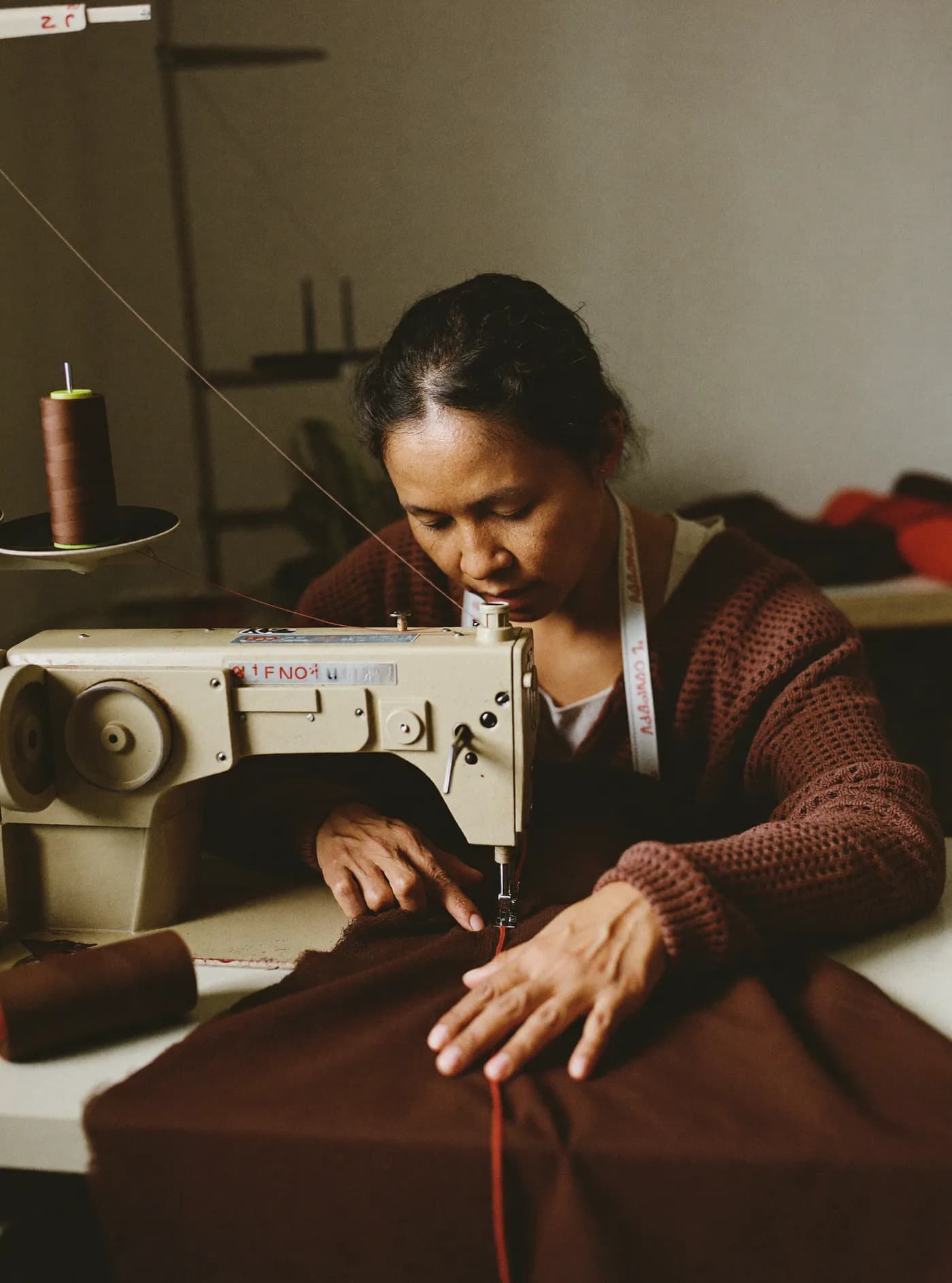 A seamstress sewing chocolate-brown fabric at a sewing machine
